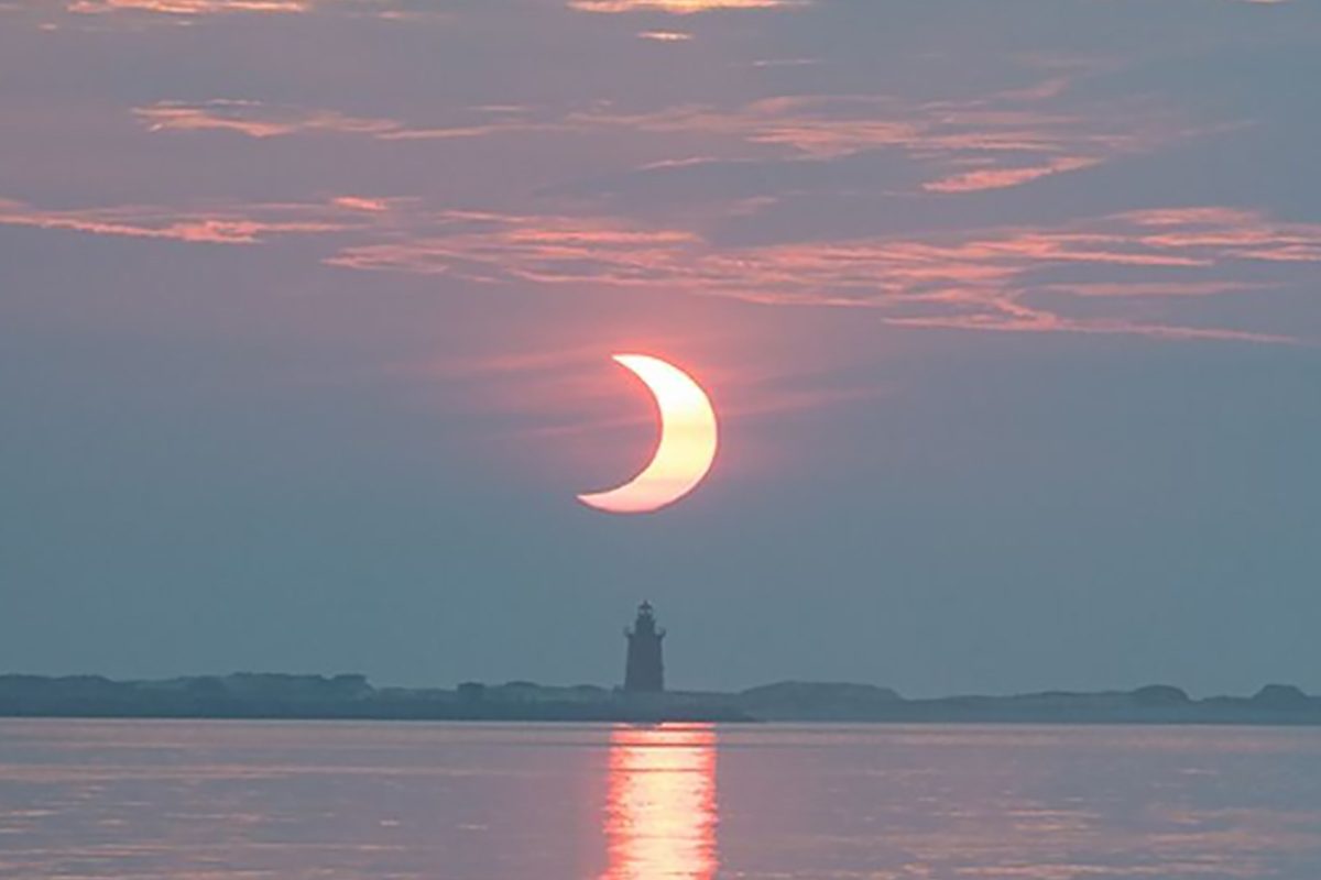 A partial solar eclipse rising behind Delaware Breakwater Lighthouse on at Lewes Beach in Delaware, USA, 10 June 2021. Credit: NASA/Aubrey Gemignani