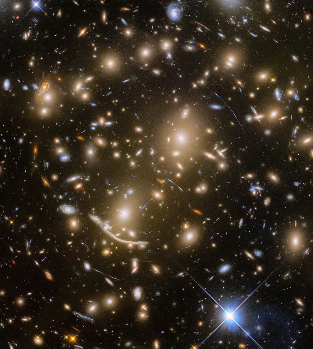 This image of Abell 370, a galaxy cluster 4 billion lightyears away, shows several arcs of light, including the 'Dragon Arc' (lower left of centre). These arcs are caused by gravitational lensing, when light from distant galaxies is warped by the cluster's gravity. Credit: NASA, ESA/Hubble, HST Frontier Fields