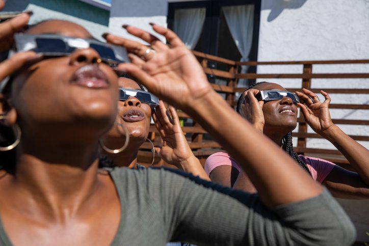 Women observing a solar eclipse safely with eclipse glasses. Credit: Leo Patrizi / Getty