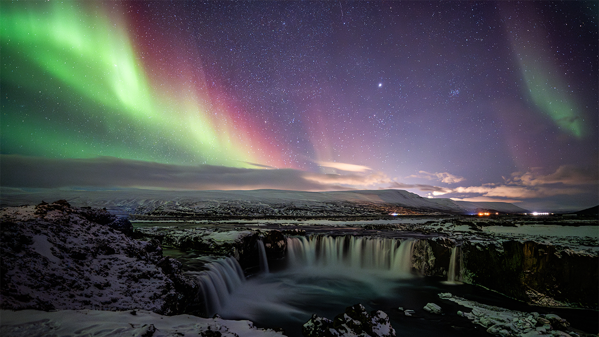 Colourful Aurora and Waterfall © Yifan Cao (China), Best Newcomer. Taken with a Nikon Z 6III camera, 16 mm f/2.2, ISO 4000, 6-second exposure. Location: Goðafoss Waterfall, Þingeyjarsveit, Iceland, 27 February 2025