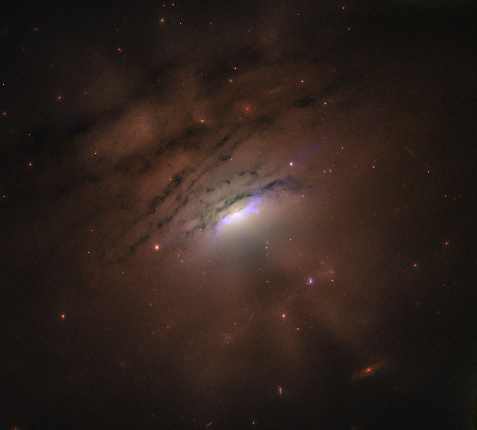 Cone-shaped shadows emanating from the bright centre of galaxy IC 5063 could be cast by the dusty ring surrounding the supermassive black hole at its centre. Credit: NASA, ESA, STScI and W.P. Maksym (CfA)