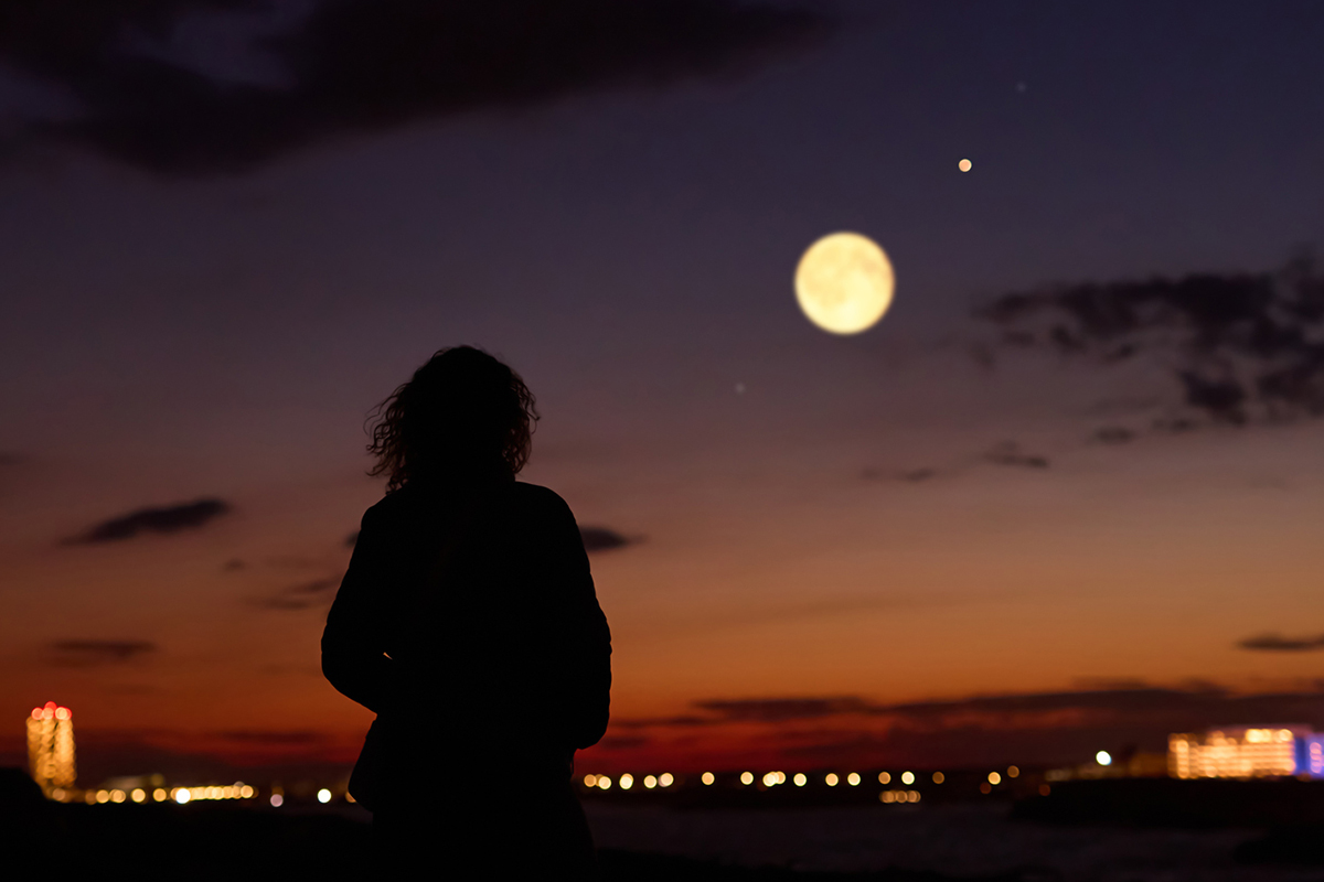Artist's impression of a woman observing the full Moon and planet. Credit: m-gucci / Getty Images