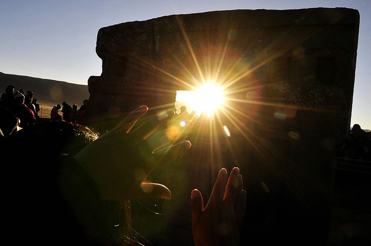 Thousands of people raise their hands to receive the first rays of the Tata Inti Sun god through the 'Gateway of the Sun' during the Aymara New Year celebration on 21 June 21 2009, Tiwanaku, Bolivia. Credit: AIZAR RALDES/AFP via Getty Images)