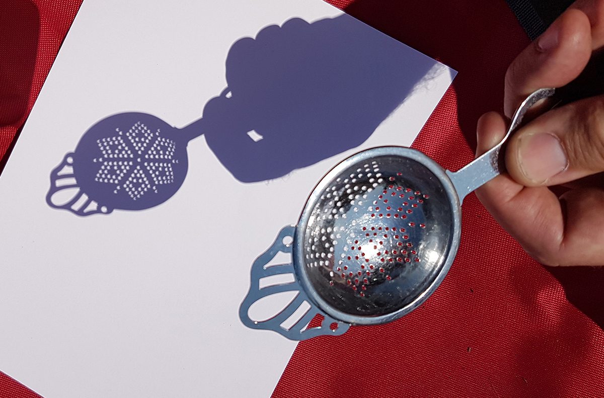 Each hole in this decorative tea strainer acts like a projection pinhole, producing a tiny image of the eclipsed Sun