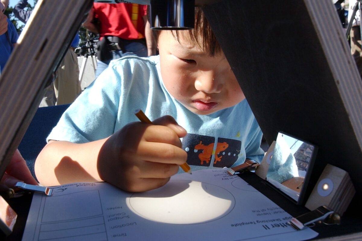 This boy is drawing the outline of a partial solar eclipse projected onto a piece of card. Here, the eclipse is projected through a specially-configured telescope, making the projection much bigger. Photo by Justin Sullivan/Getty Images