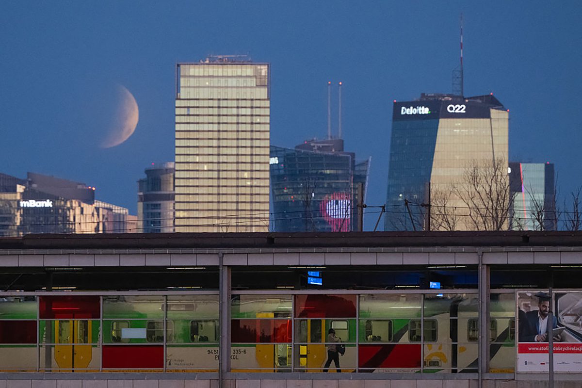A passenger gets off a train as the partial lunar eclipse appears over Warsaw, Poland, 28 August 2026. Photo by Sergei GAPON / AFP via Getty Images