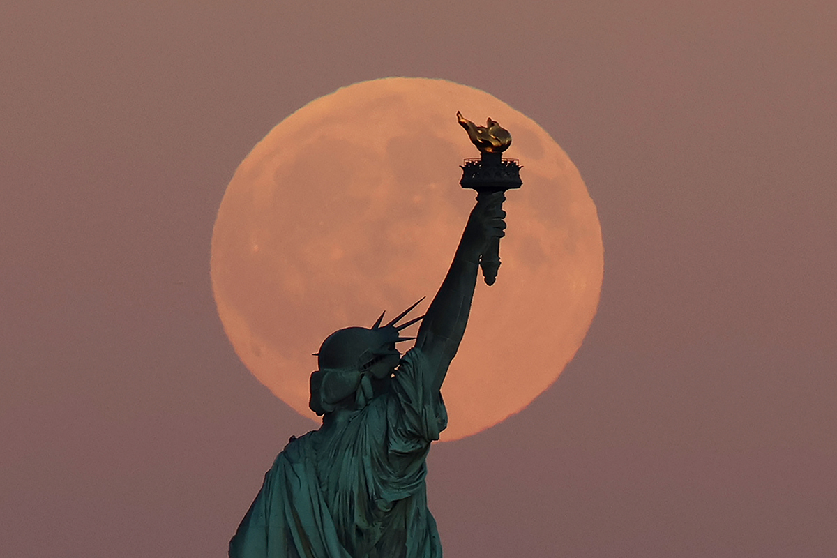 The Harvest Supermoon rises behind the Statue of Liberty in New York City, 6 October 2025. Photo by Gary Hershorn/Getty Images