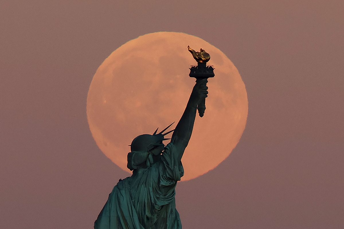 The Harvest Supermoon rises behind the Statue of Liberty in New York City, 6 October 2025. Photo by Gary Hershorn/Getty Images