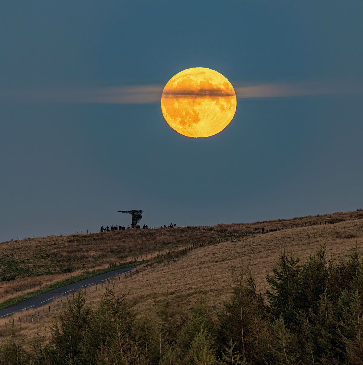 The 18 September 2024 Harvest Moon dissected by cloud, captured by Lee Mansfield over the Singing Ringing Tree sculpture, Burnley, Lancashire, UK. The Singing Ringing Tree is a wind powered sound sculpture resembling a tree set in the landscape of the Pennine hill range overlooking Burnley, in Lancashire